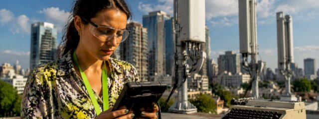 Un inginer inspectează antenele 5G montate pe acoperișul unei clădiri.